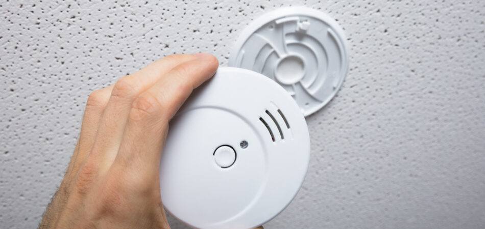 Person,repairing,the,smoke,detector,on,the,ceiling,wall